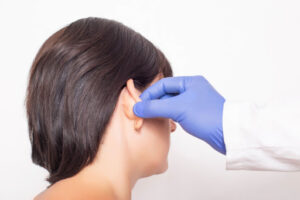 A woman has her ears looked at by a surgeon.