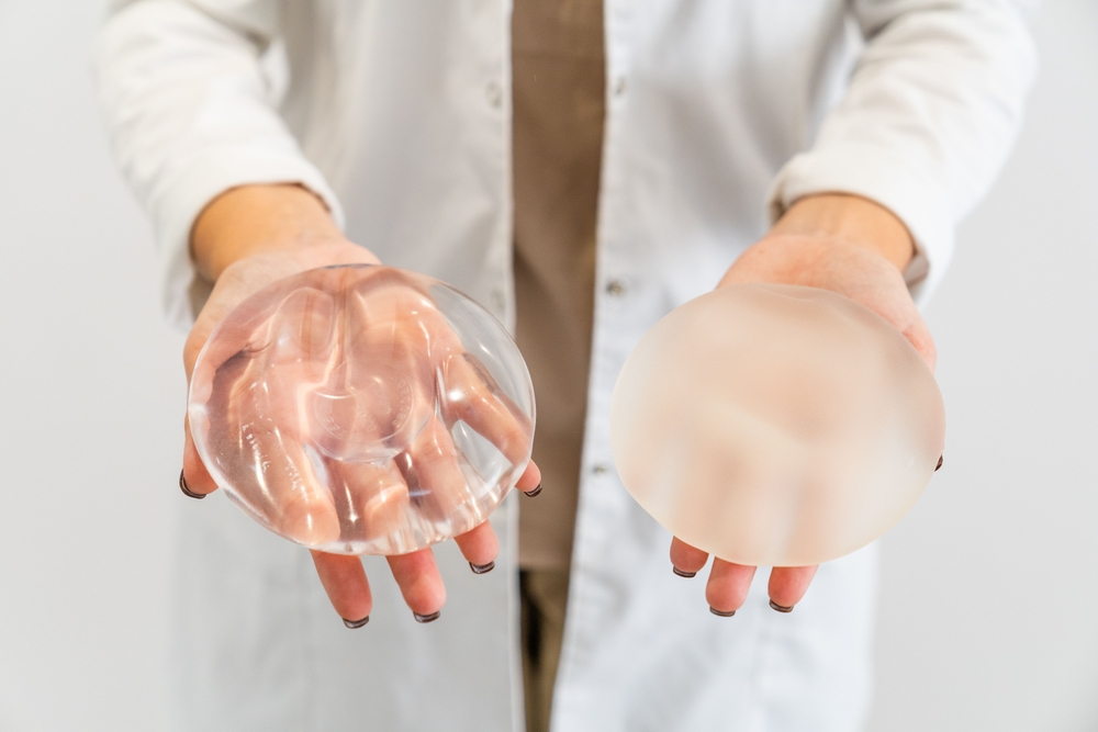 doctor's hands holding two different types of breast implants