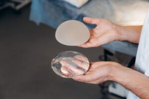 plastic surgeon holding two types of breast implants